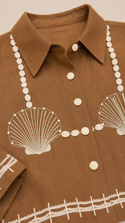 Close-up detail of lapel collar and shell embroidery on brown top